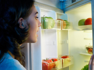 a woman looking in the fridge for foods that help you sleep